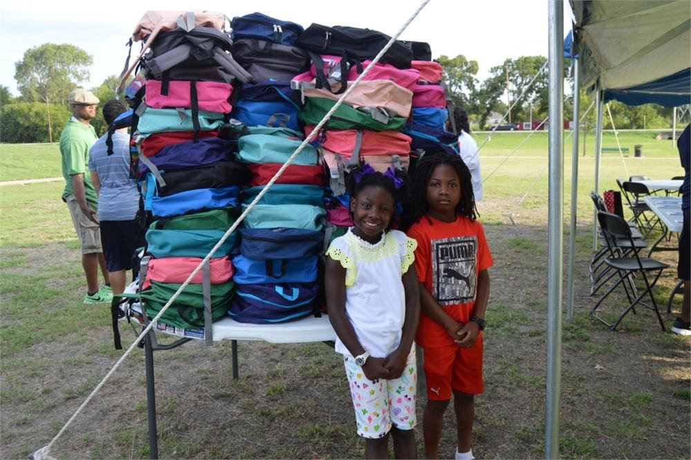 Two Kids Standing in Front of Backpacks
